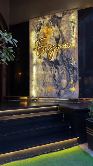 Enigma's backlit onyx wall with the gold script logo